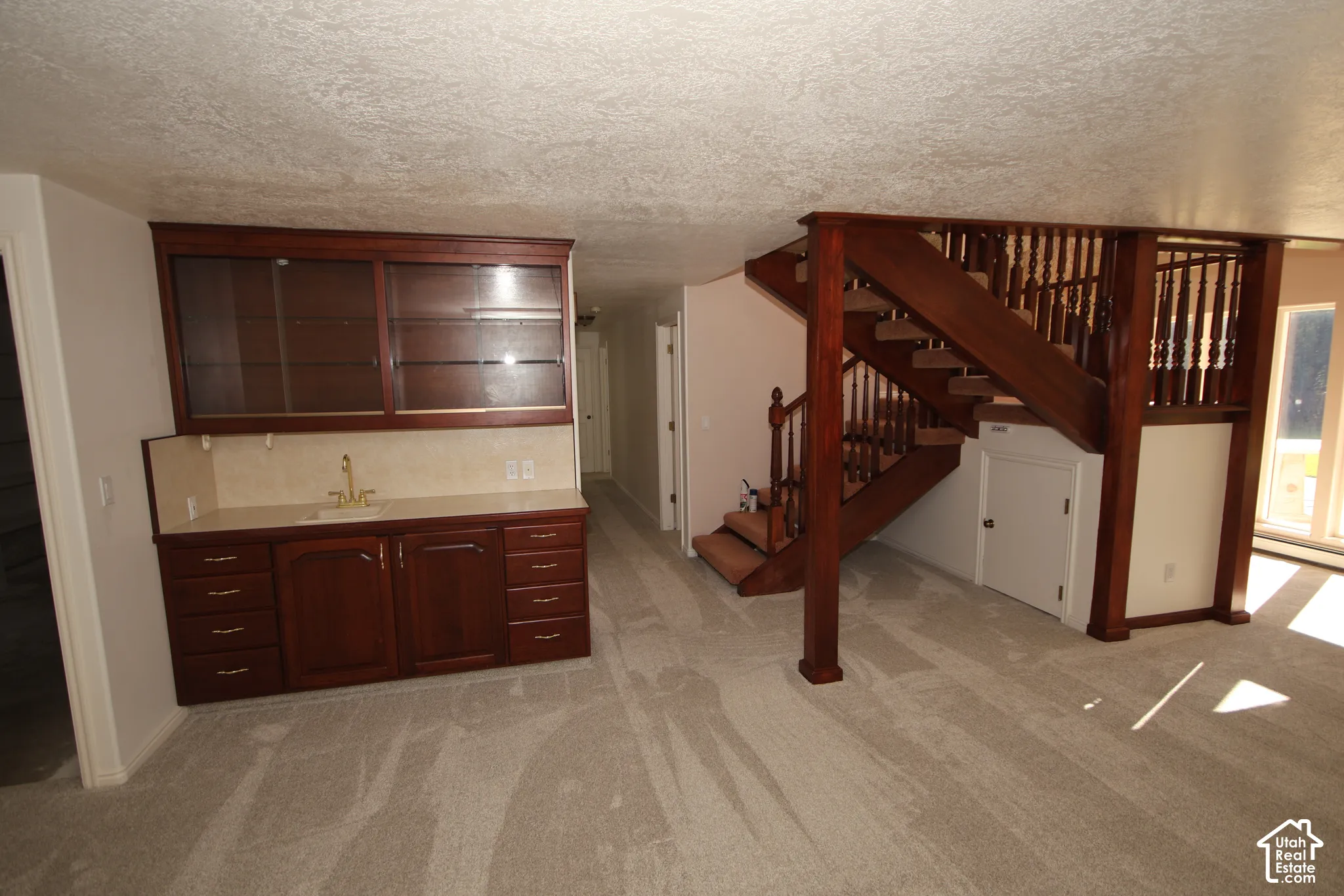 Built-in wet bar with wood-finish cabinetry, a single basin sink, and ample storage