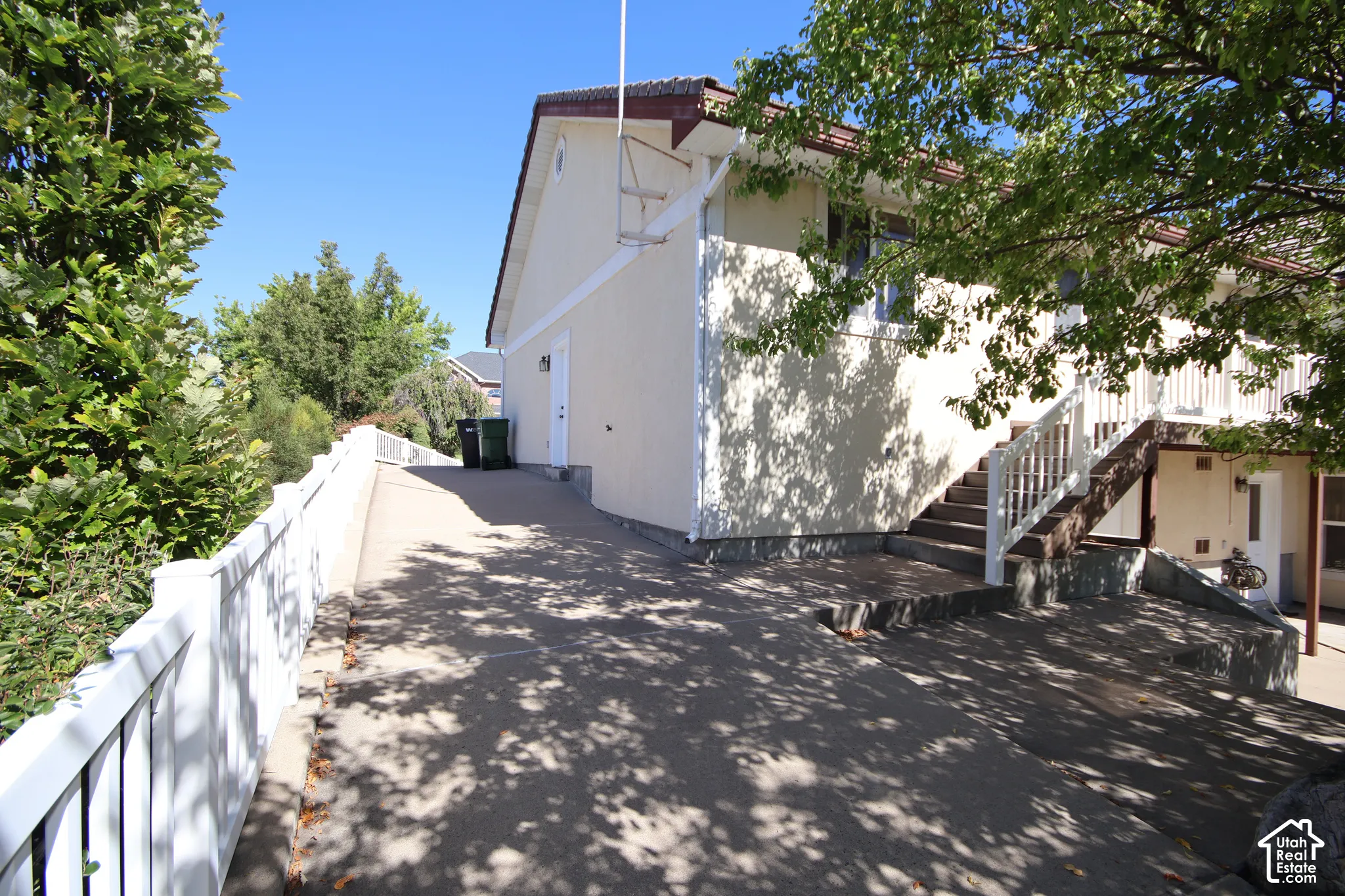 Stucco exterior with a tiled roof, featuring an exterior staircase with white railings, and a concrete driveway