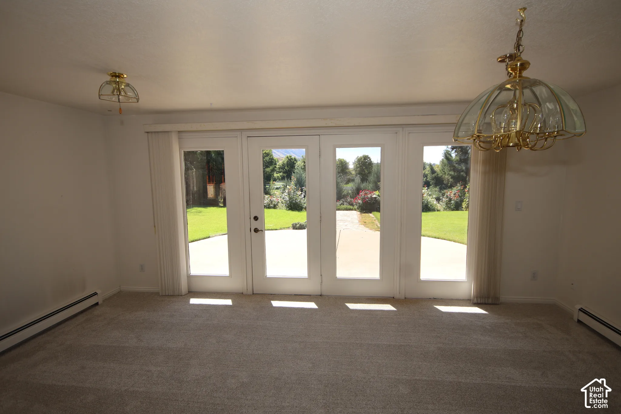 Four-panel glass French doors open to an expansive backyard with a patio and manicured lawn