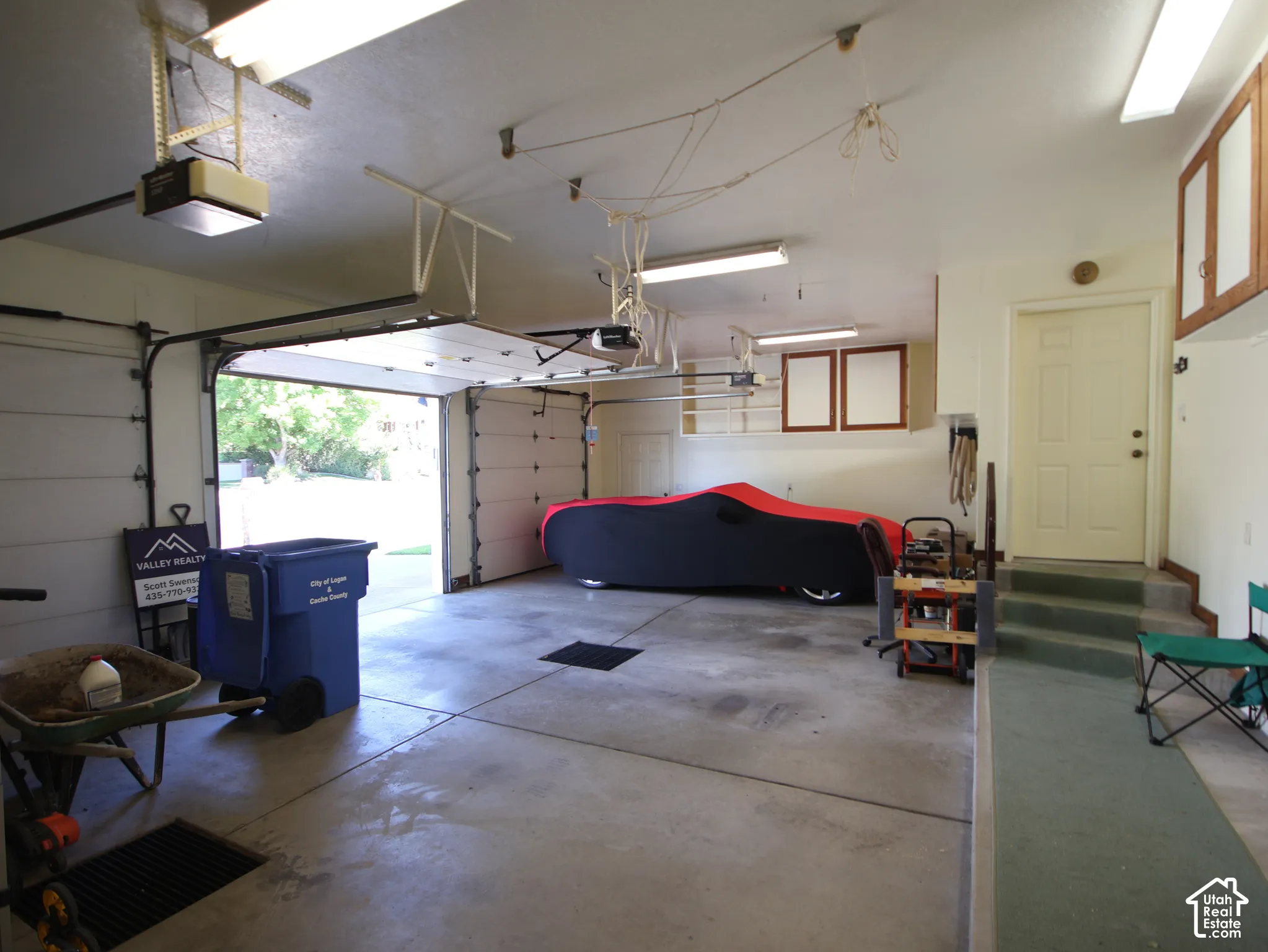 Concrete flooring garage with dual garage doors, built-in cabinetry, and direct interior access