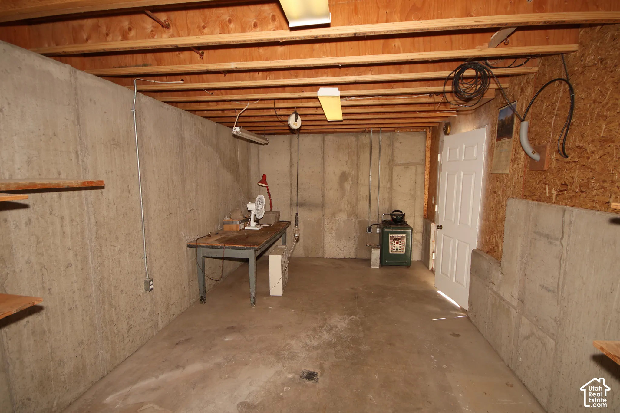 Exposed wood ceiling joists, concrete flooring, and a paneled white door