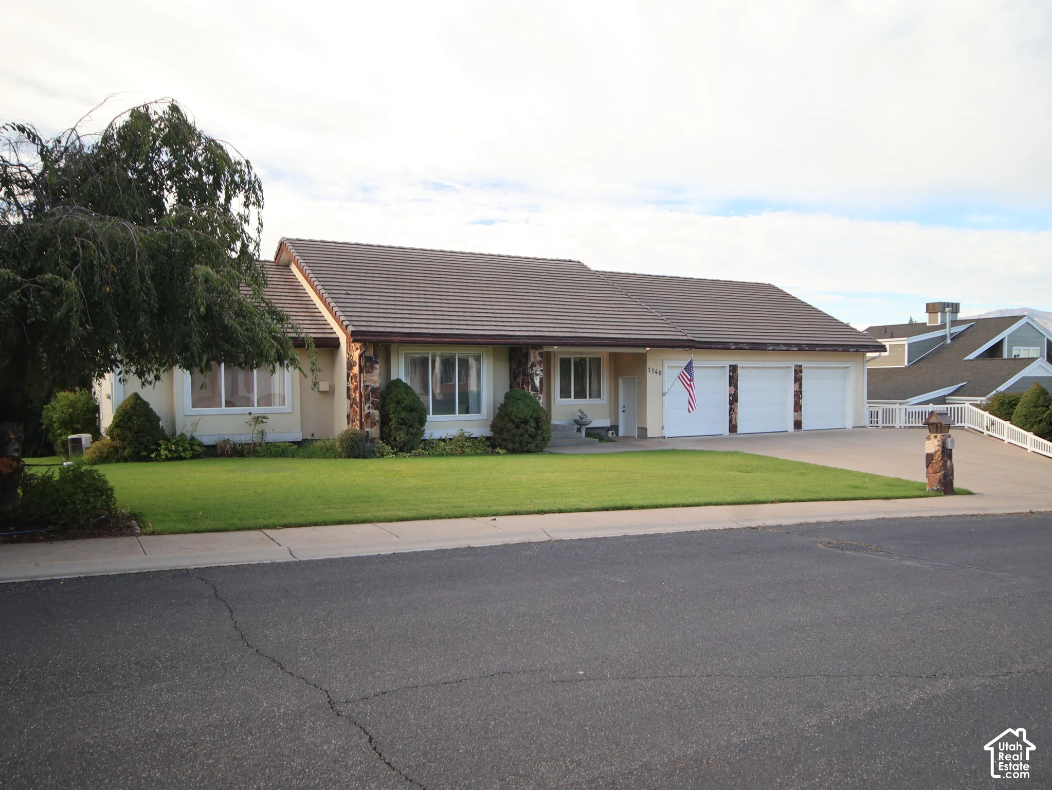 Single-story residence featuring a tile roof, stone accents, and a three-car garage