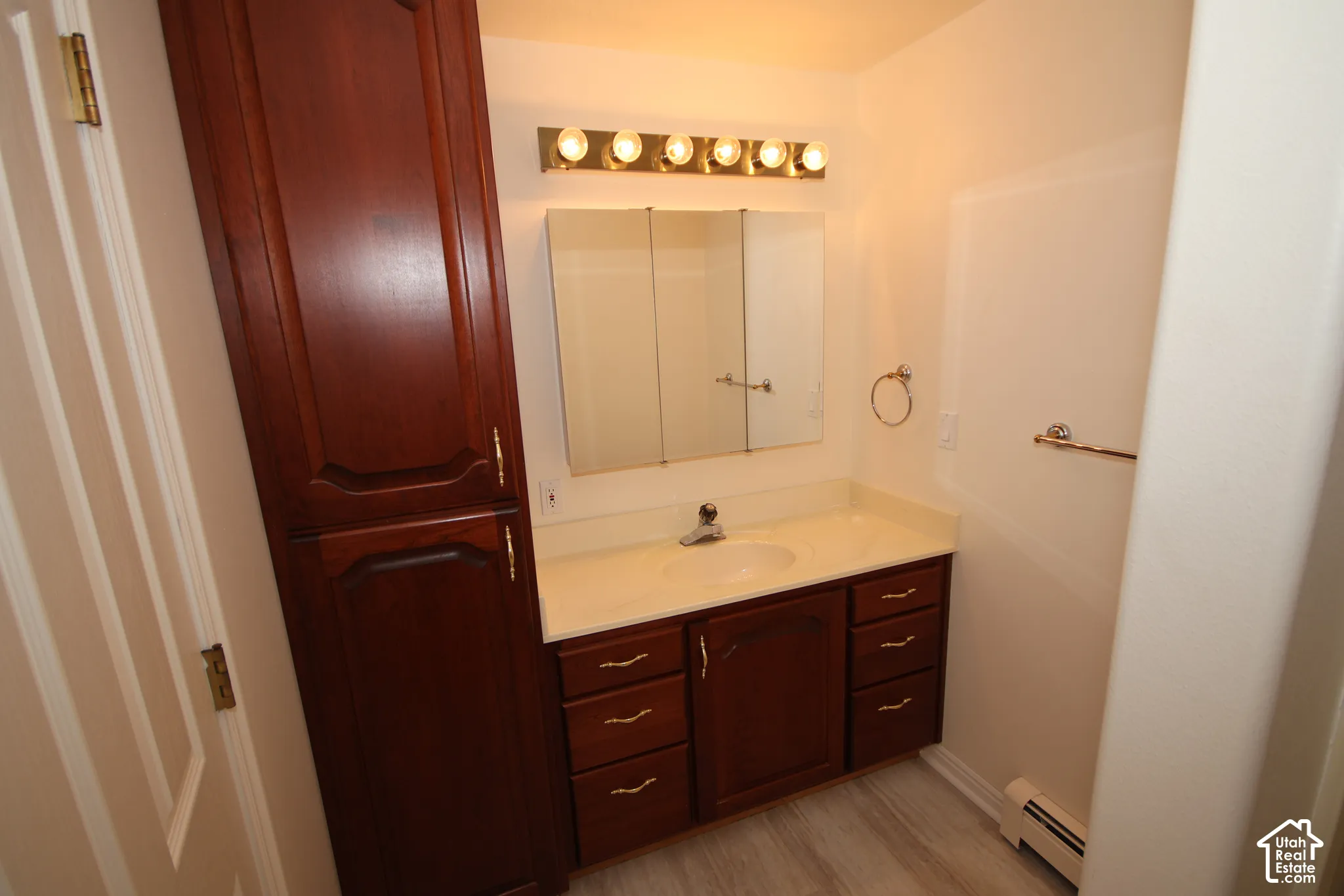 Wood-finish vanity with an integrated sink and light countertop, complemented by a tall, matching wood-finish storage cabinet