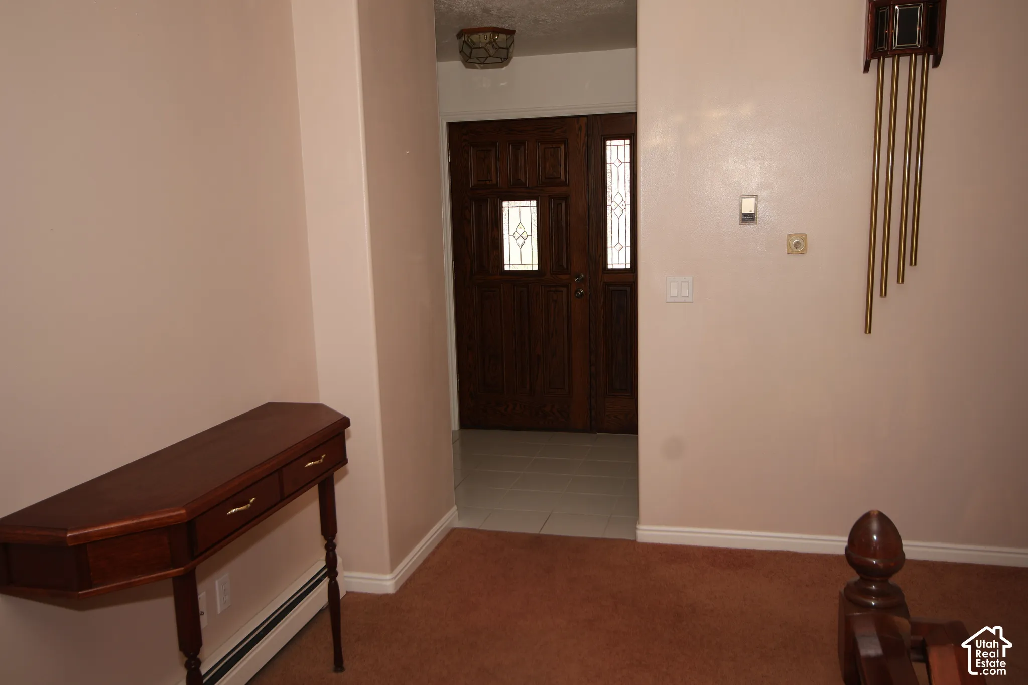 Entryway with warm-toned walls, brown carpeting, and a dark wood double door with leaded glass panels
