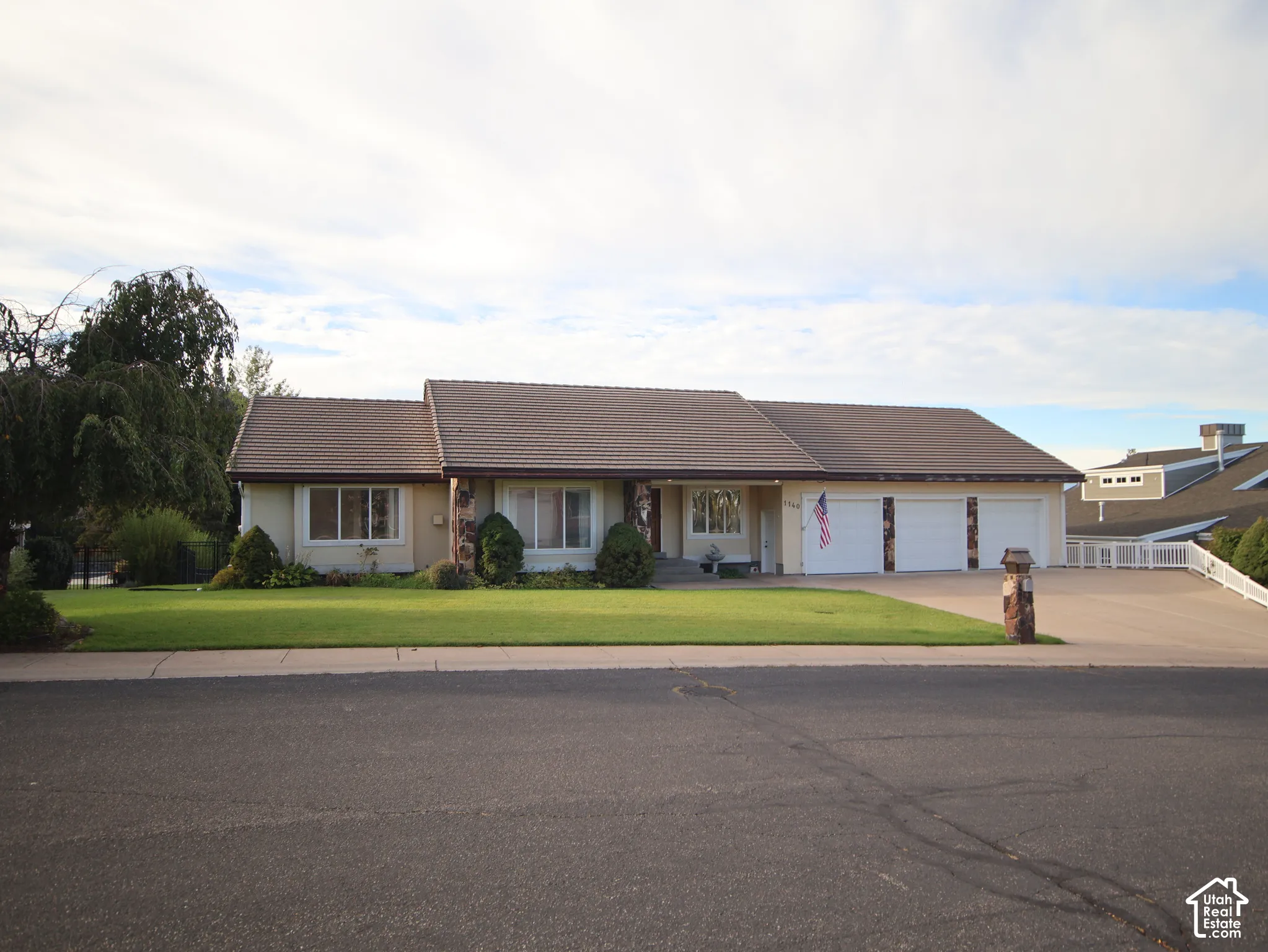Single-story residence featuring a tile roof, light-toned exterior, and an attached three-car garage