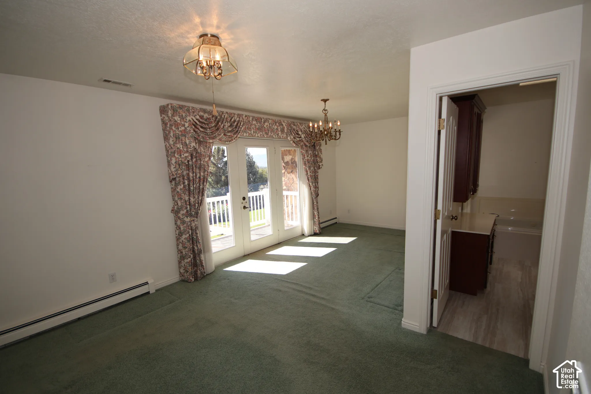 Room with wall-to-wall carpeting, French doors with exterior balcony, and overhead chandeliers