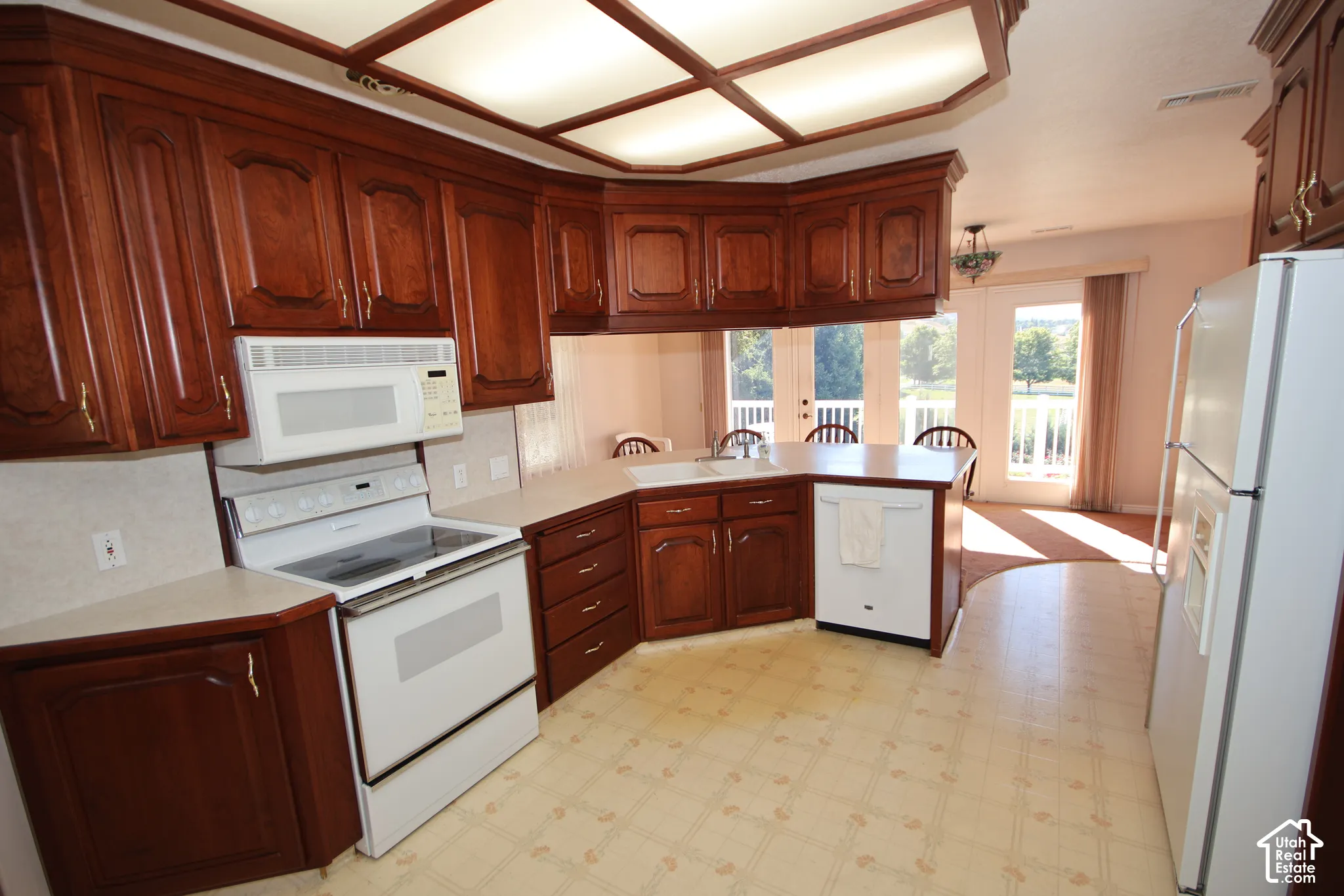 Wood-finish cabinetry, built-in microwave, white electric range, and a white refrigerator