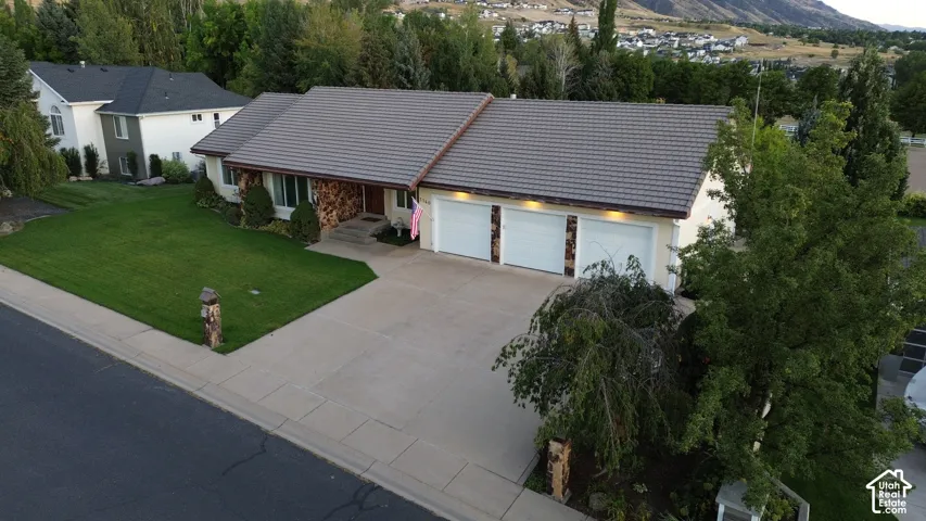 Single-story residence featuring a tile roof, stone accent wall, and a three-car garage