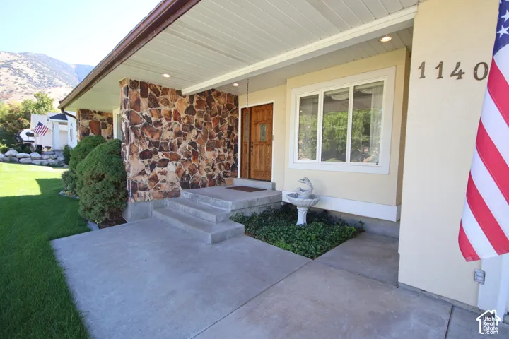 Stone-clad exterior accent, wood-finish entry door, concrete steps, built-in window, and a decorative fountain