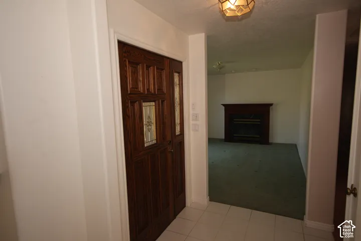 Tiled entryway with dark wood-paneled door featuring decorative glass inserts with connections to Formal Living room and dining area