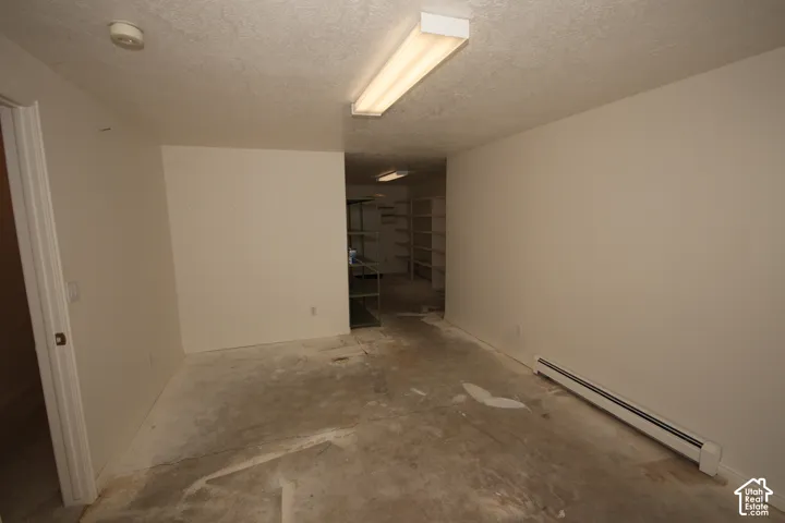 Unfinished space with smooth painted walls, fluorescent overhead lighting, and built-in shelving units