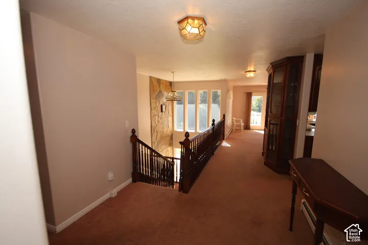 Staircase with wood banister and railing, stone accent wall, and multiple windows