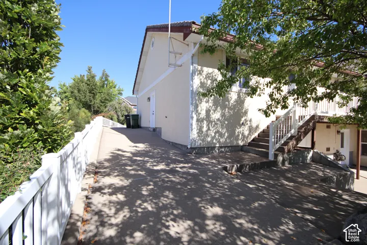 Stucco exterior with a tiled roof, featuring an exterior staircase with white railings, and a concrete driveway
