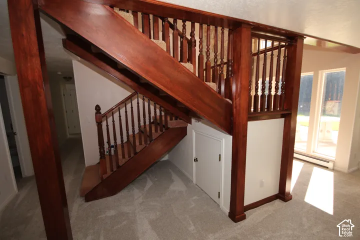 Hardwood staircase with ornate balusters, carpeted treads, and a built-in under-stair storage door