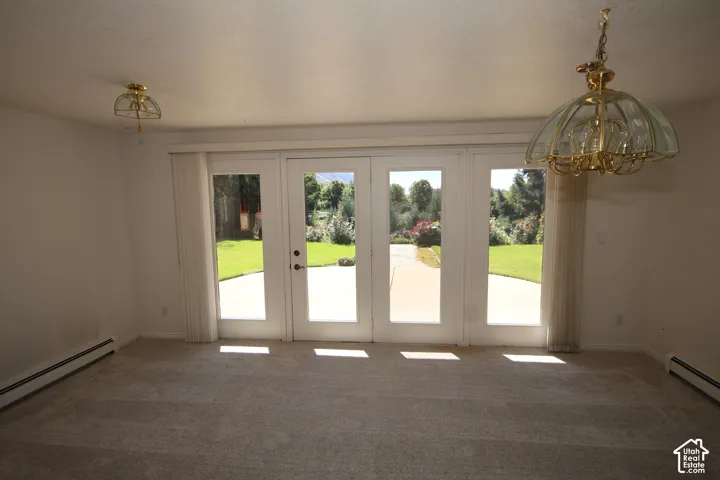 Four-panel glass French doors open to an expansive backyard with a patio and manicured lawn