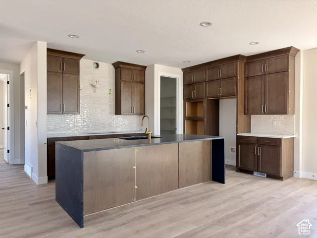 Chef's kitchen featuring waterfall island, stacked cabinets and tile backsplash