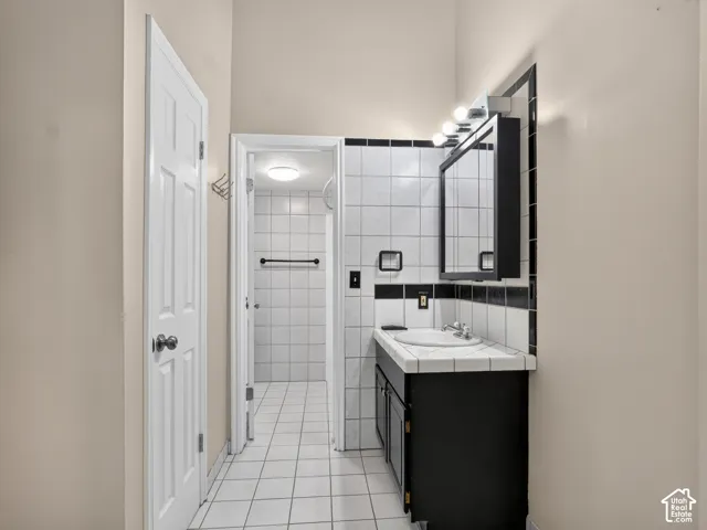 Black vanity with a white basin sink, framed mirror, and integrated lighting