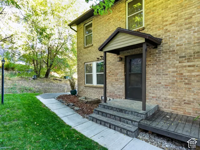 Brick exterior with a covered entry, stone-look steps, and a dark-paneled front door