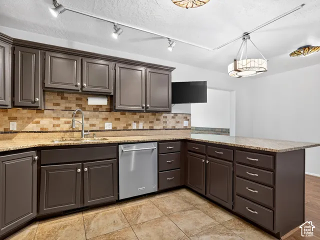 Dark brown cabinetry with silver hardware, granite-style countertops, a tiled backsplash, and ceramic tile flooring