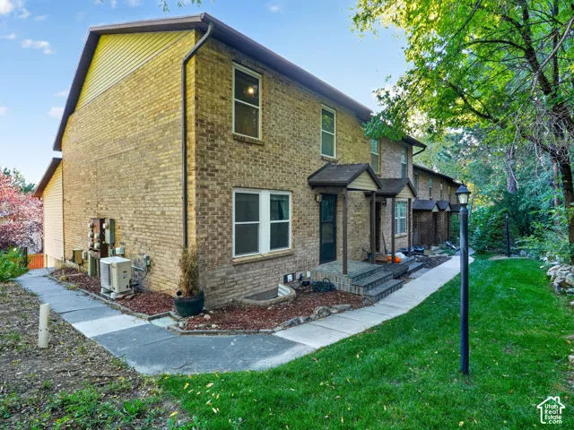 Brick exterior with multiple windows, covered entryways, and a manicured lawn