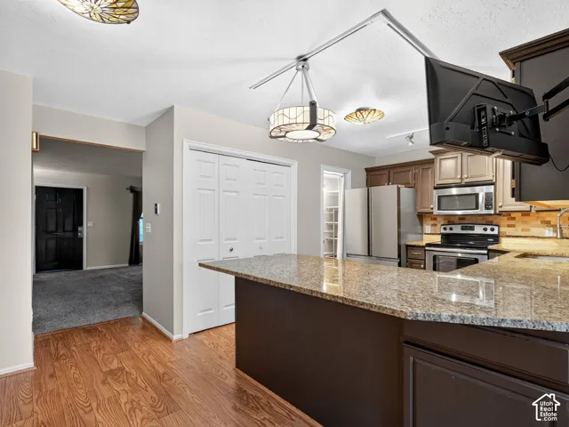 Wood-finish flooring with a multi-tone kitchen island featuring a stone-finish countertop