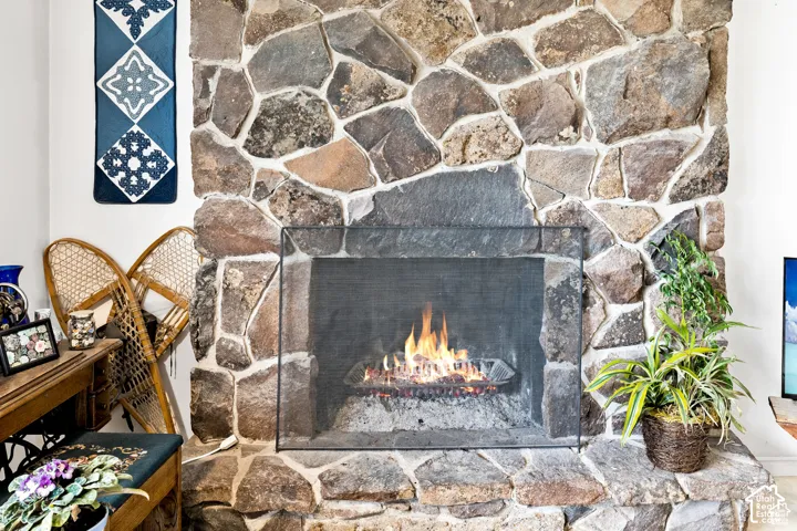 Stone-clad fireplace featuring a hearth and a mesh fire screen