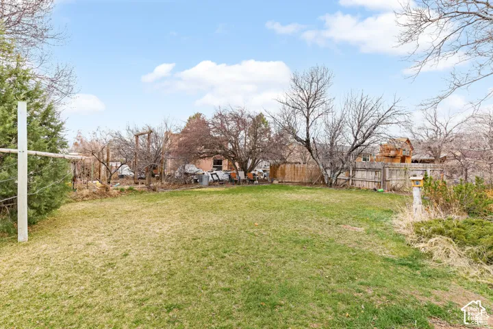 Expansive grassy yard with mature trees and a wood fence