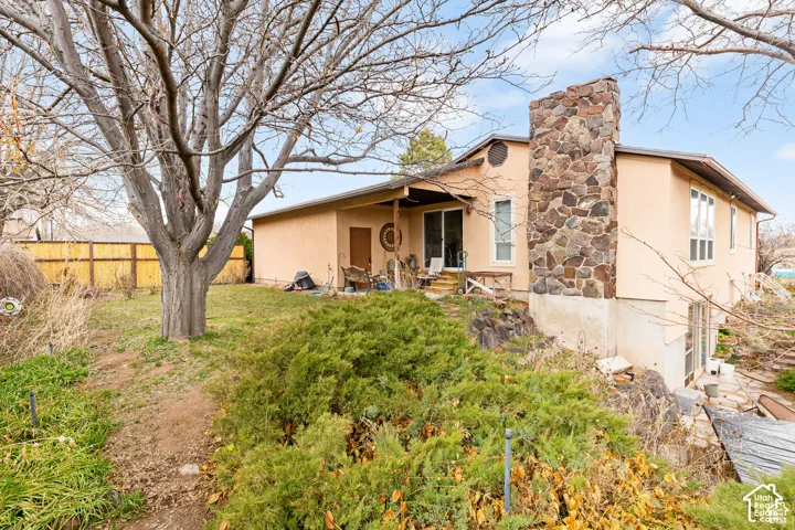 Stucco exterior with a stone chimney feature, multiple windows, and a sliding glass door