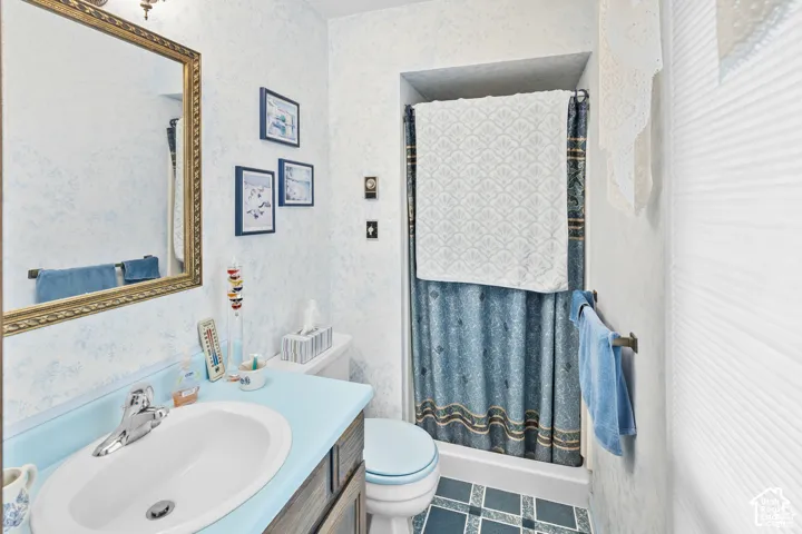Bathroom featuring a vanity with an integrated sink, a framed mirror, a shower with a patterned curtain, and tiled flooring