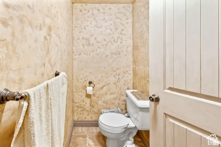 Textured wall finish, tile flooring, white panel door, and bronze hardware