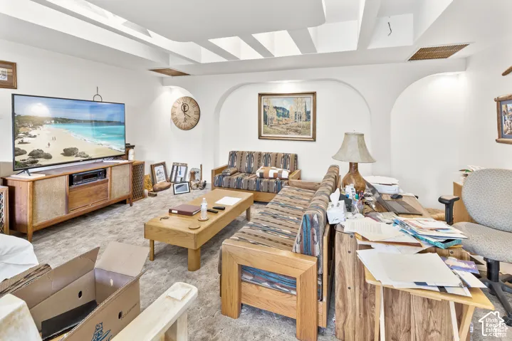 Tray ceiling design with recessed lighting, arched wall openings, and carpeted flooring
