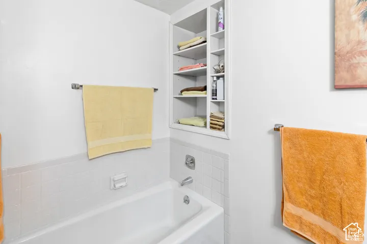 White tub with chrome fixtures and white tiled surround