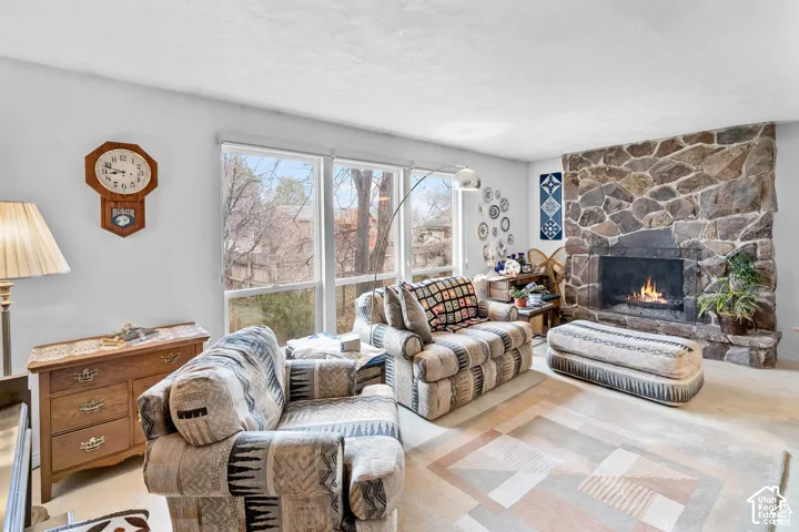 Stone-clad fireplace with a raised hearth, large windows, light-colored walls, and textured ceiling