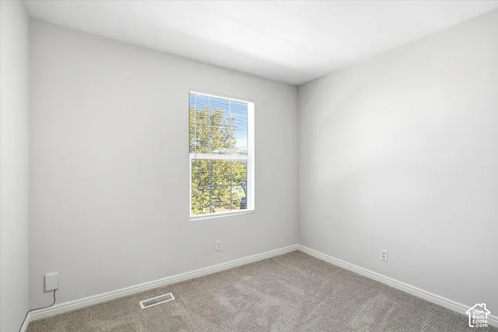 Carpeted flooring, white painted walls, and a window with blinds