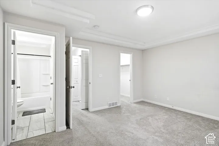 Tray ceiling, recessed lighting, carpeted flooring, full bathroom with tiled flooring, built-in closet