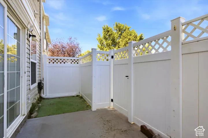 Enclosed patio space featuring a concrete pad and white privacy fencing with lattice detail