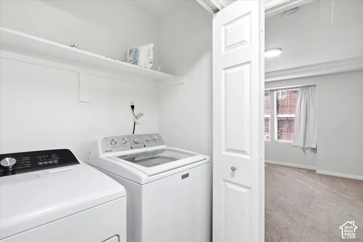 Laundry area with a built-in shelf and panel door entry to a carpeted room with a window