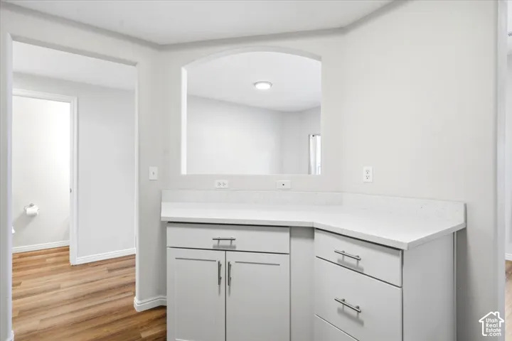 Corner counter with quartz countertops, white cabinetry, and brushed nickel hardware