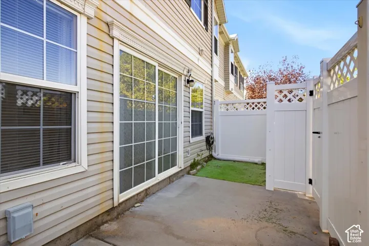Concrete patio area with a white vinyl privacy fence and gate