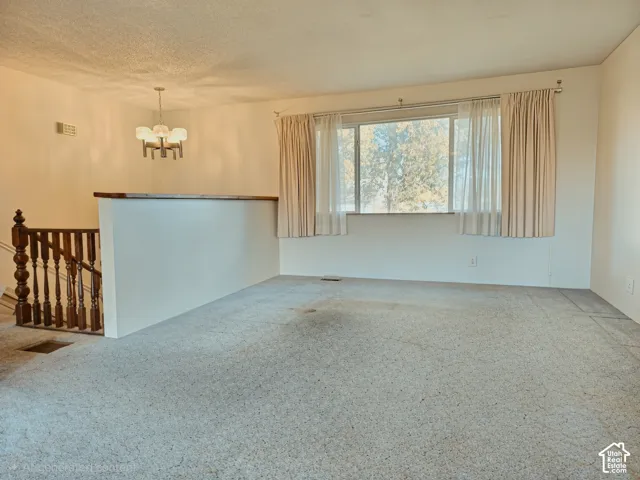 Large picture window with exterior natural scenery, custom-style multi-arm ceiling light fixture, and wooden staircase balustrade with turned newel posts