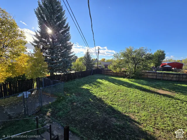 Expansive backyard featuring a fenced perimeter, mature trees, and a concrete patio area