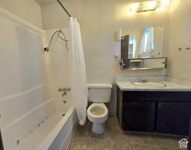 Full bathroom featuring a tub-shower combination, dark wood-finish vanity, stone-finish countertop with integrated sink, wall-mounted medicine cabinet, and tile flooring