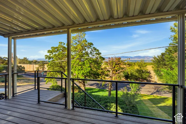 Covered deck featuring wood-finish decking, black metal railing, and cable infill
