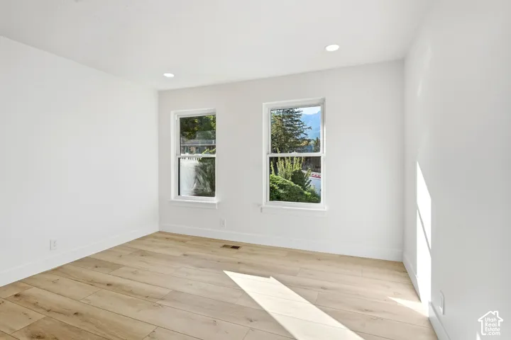 Recessed lighting, light wood-finish flooring, and two white-framed windows