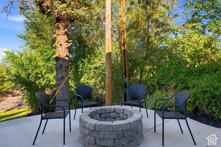 Outdoor patio featuring a stone-finish fire pit surrounded by mature trees