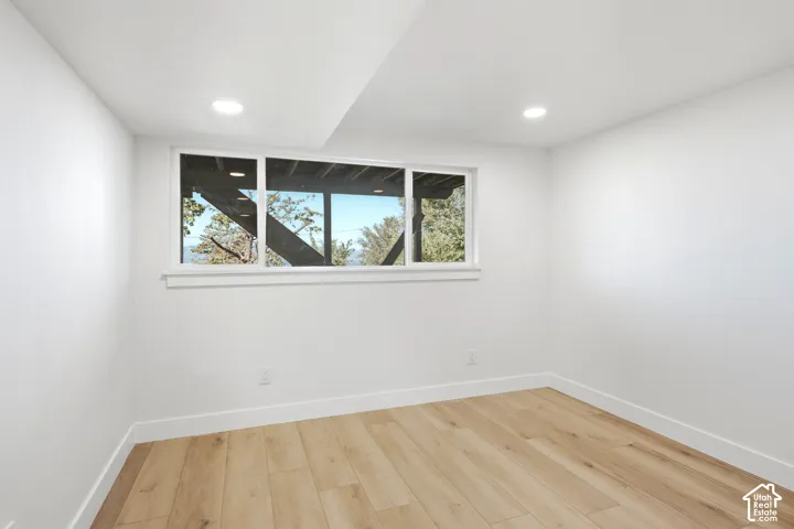 Recessed lighting, wood-finish flooring, white walls, and a large window