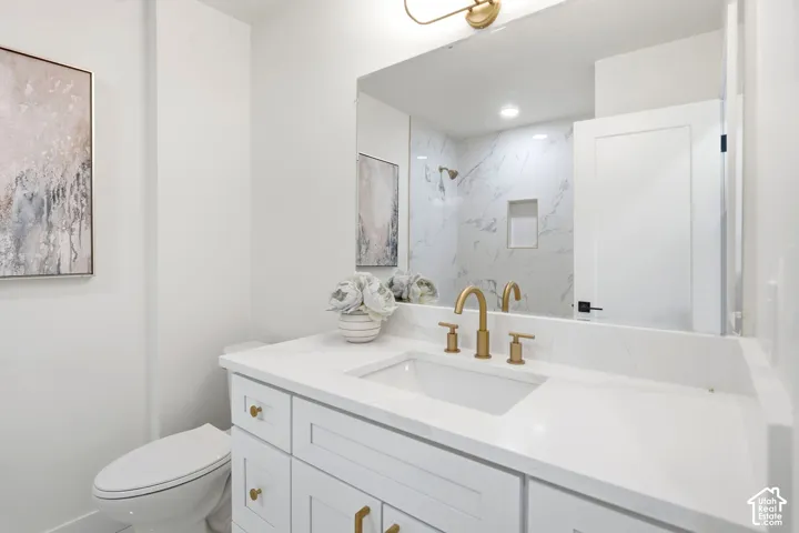 White vanity with gold-finish hardware, undermount sink, and white countertop