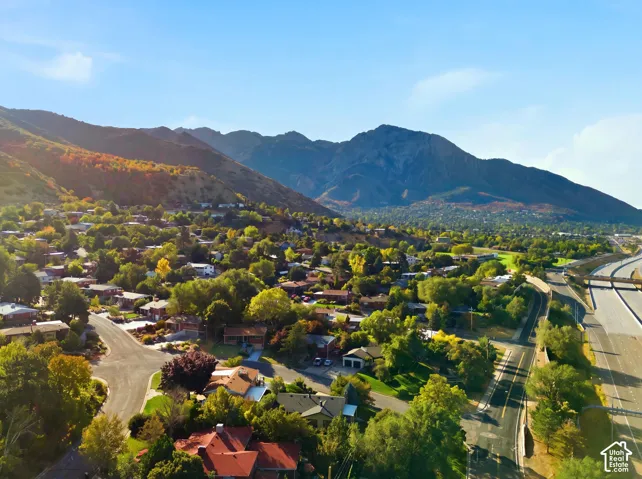 Mountainous backdrop, residential area, mature trees, multi-lane highway access, paved roads