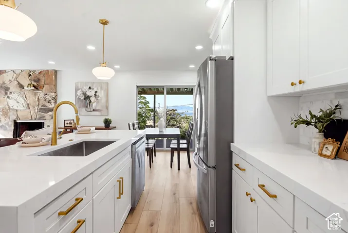 Gourmet kitchen featuring white cabinetry, gold-tone hardware, wood-finish flooring, and a stone fireplace