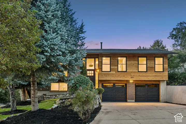 Modern exterior featuring a wood-panel facade, two attached garages, and a concrete driveway